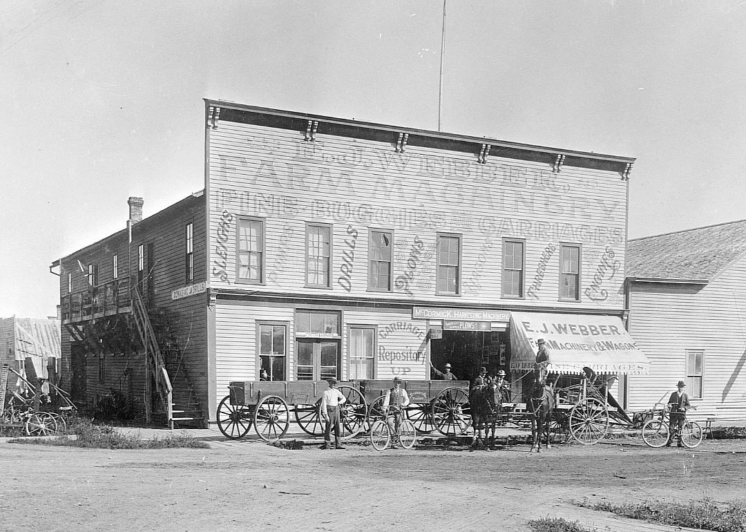 Rural farm machinery store with wagons and people