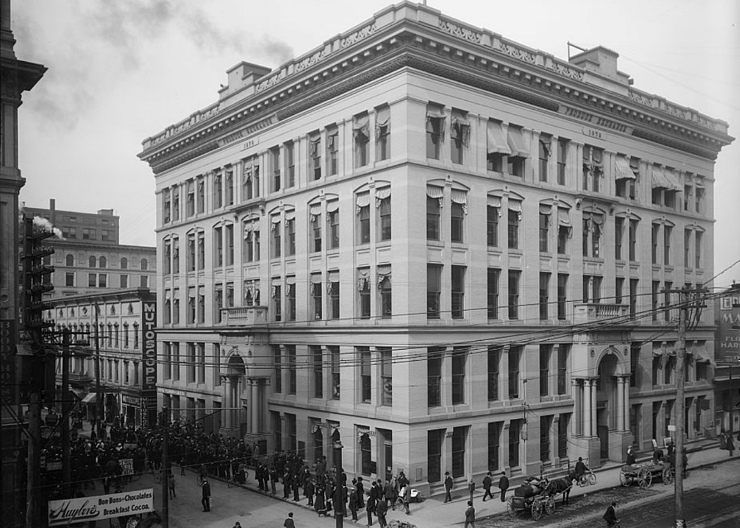 Six story stone building in downtown with people on sidewalk